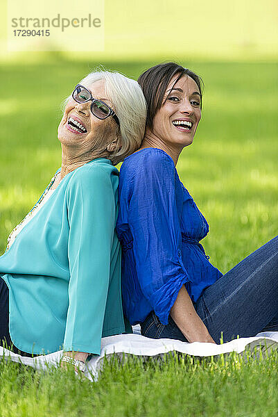 Lächelnde ältere Frau  die mit einer Frau im mittleren Erwachsenenalter in einem öffentlichen Park sitzt