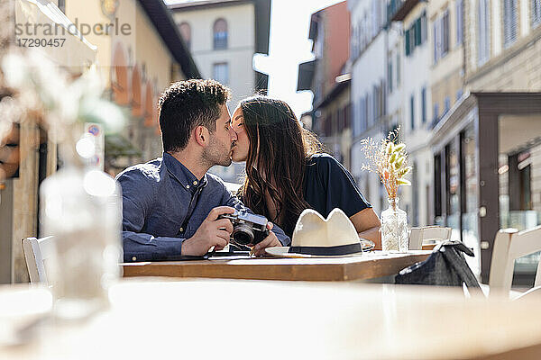 Touristenpaar küsst sich in einem Straßencafé