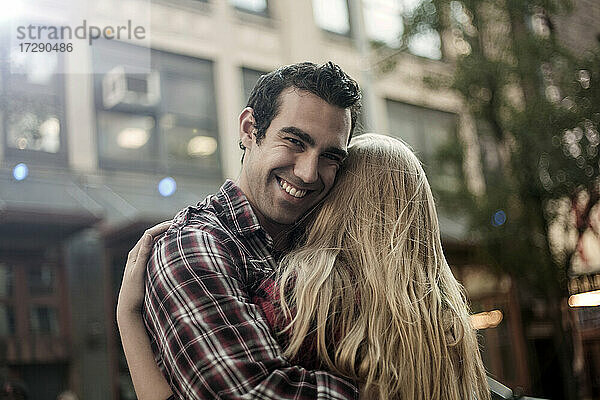 Lächelnder Freund umarmt Freundin in der Stadt