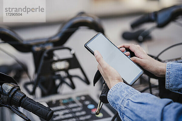 Frau benutzt Smartphone  um in der Stadt ein Fahrrad zu mieten