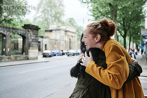 Glückliche Freundinnen umarmen sich auf der Straße