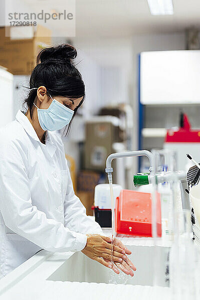 Ältere Forscherin mit Gesichtsschutzmaske beim Händewaschen im Labor