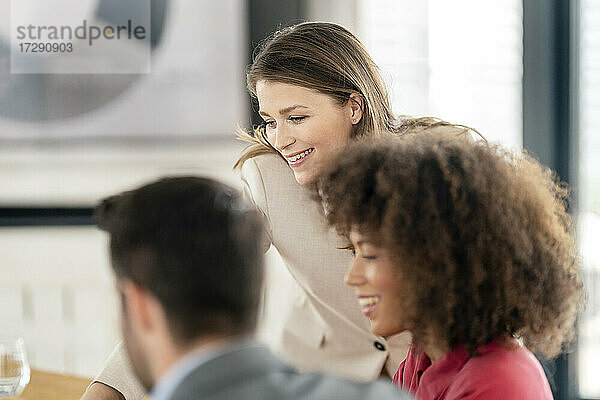 Lächelnde männliche und weibliche Fachleute  die im Büro diskutieren