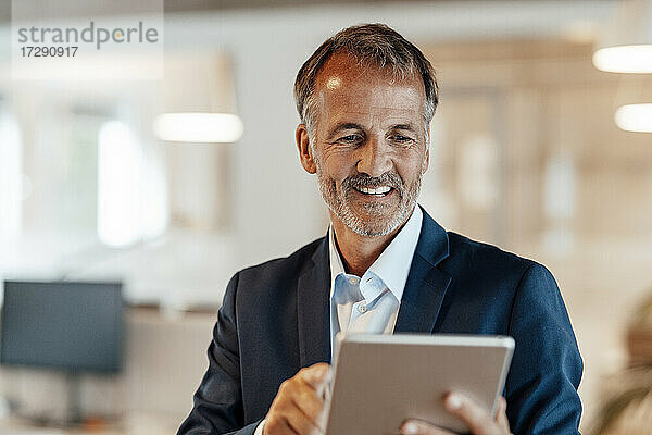 Männlicher Unternehmer benutzt digitales Tablet im Büro