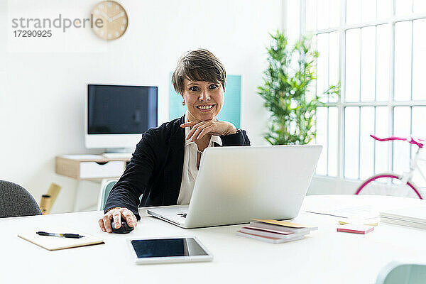 Geschäftsfrau sitzt mit Laptop am Schreibtisch im Büro