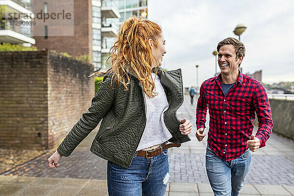 Lächelndes Paar  das sich beim Laufen auf dem Fußweg ansieht
