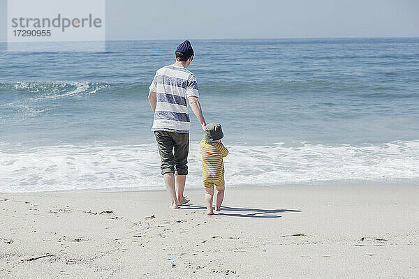 Vater mit Sohn geht am Strand zum Wasser