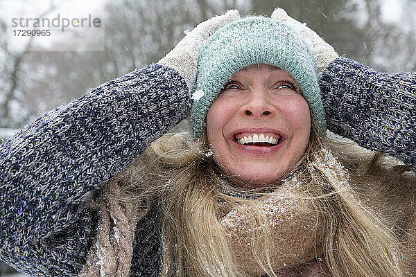 Ältere Frau mit Strickmütze  die lachend wegschaut  im Winter