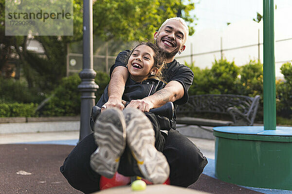 Fröhlicher Vater und Tochter spielen zusammen im Park