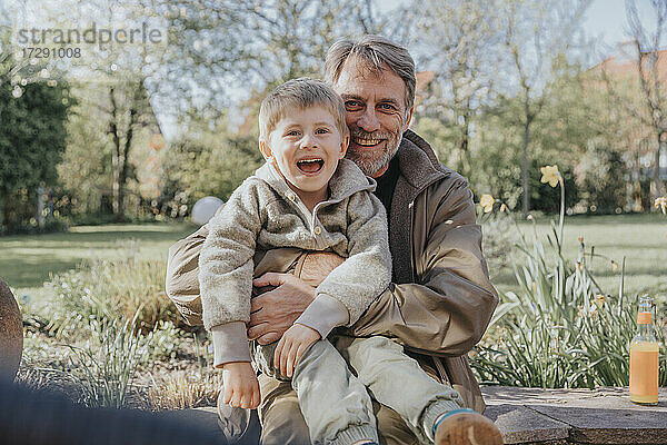 Fröhlicher Vater sitzt mit seinem Sohn im Hinterhof