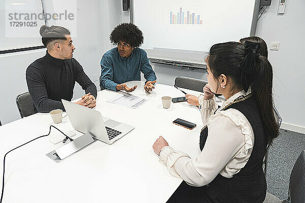 Multiethnische Unternehmer und Unternehmerinnen diskutieren im Büro