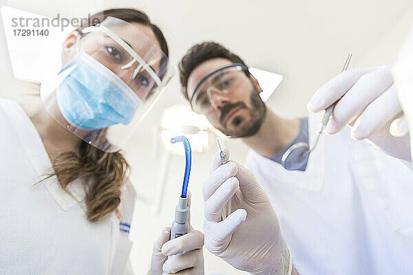 Zahnärztin mit Mitarbeiterin  die zahnärztliche Geräte in der Klinik hält