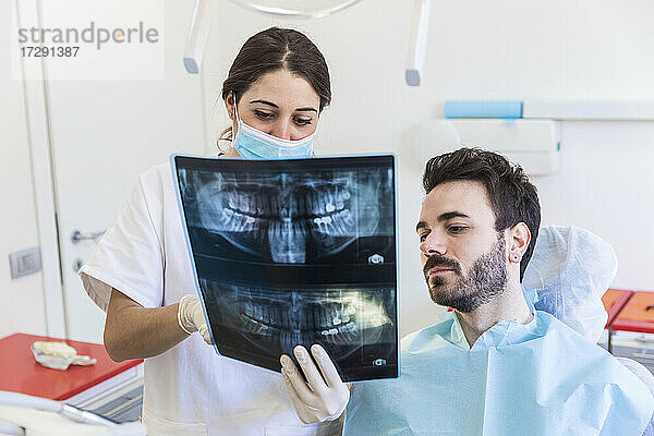 Eine Zahnärztin zeigt einem Patienten in einer medizinischen Klinik ein Röntgenbild