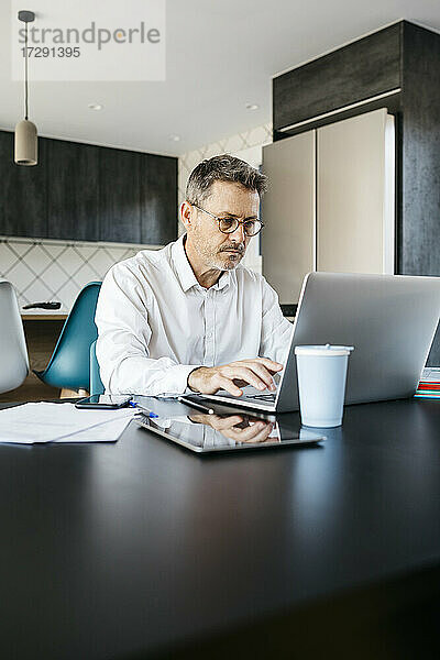 Geschäftsmann arbeitet am Laptop in der heimischen Küche im Home Office