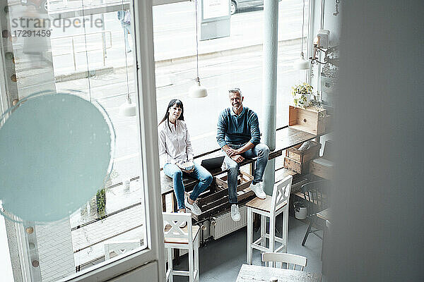 Weibliche und männliche Unternehmer sitzen am Fenster eines Cafés