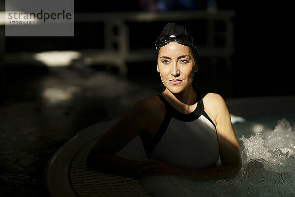 Reife Frau mit Sonnenlicht auf dem Gesicht im Schwimmbad
