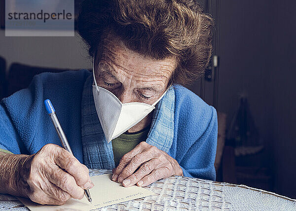 Ältere Frau schreibt zu Hause auf Papier
