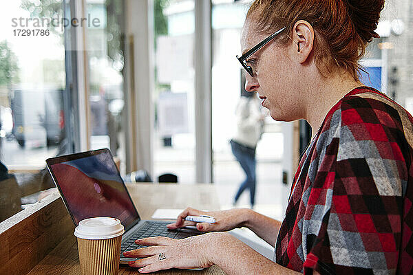 Frau mit Brille benutzt Laptop in einem Cafe