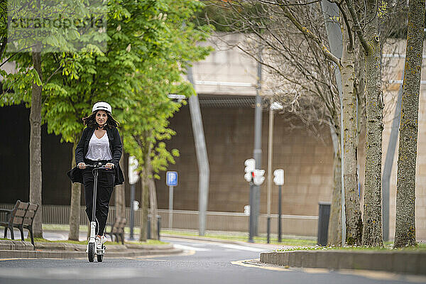 Geschäftsfrau fährt elektrischen Roller auf der Straße