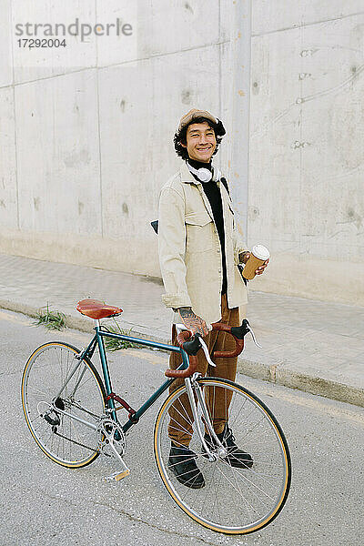Lächelnder Mann  der einen Fahrradlenker hält  während er auf dem Gehweg steht