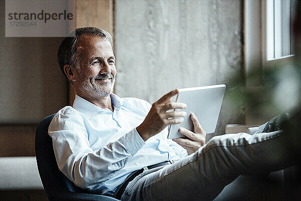 Geschäftsmann lächelnd bei der Verwendung eines digitalen Tablets im Büro