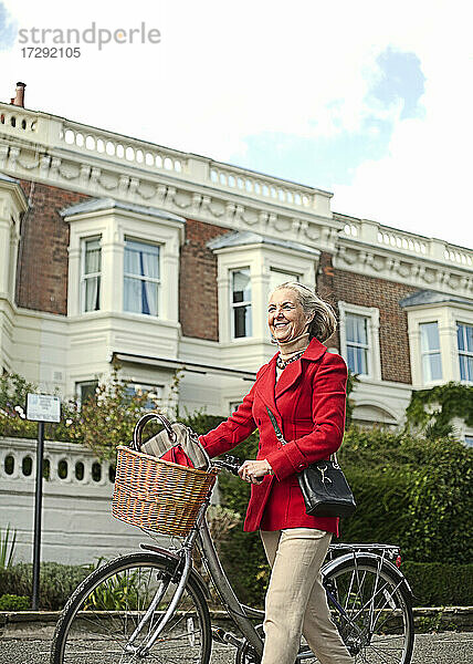 Lächelnde Frau  die in der Stadt mit dem Fahrrad spazieren geht