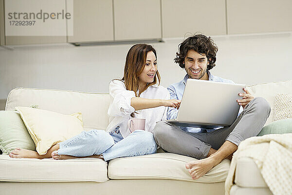 Ehepaar unterhält sich auf dem Sofa in der neuen Wohnung mit einem Laptop