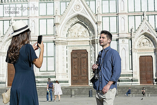 Weiblicher Tourist fotografiert Mann durch Smartphone auf der Piazza Di Santa Croce  Florenz  Italien