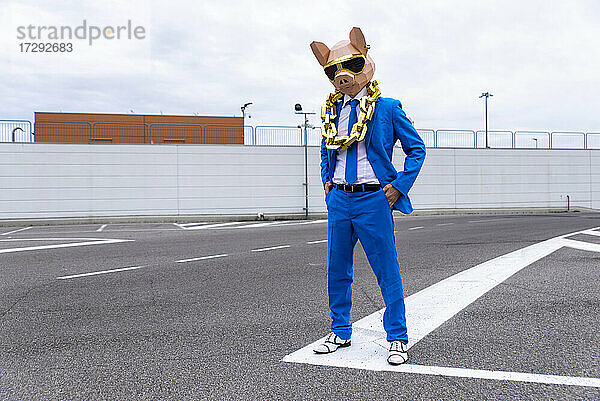 Lustige Figur mit Tiermaske und blauem Geschäftsanzug  die sich auf einem leeren Parkplatz amüsiert