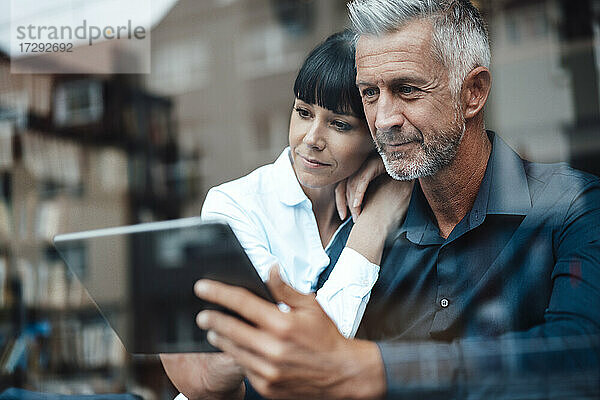 Geschäftspaar nutzt gemeinsam ein digitales Tablet in einem Café