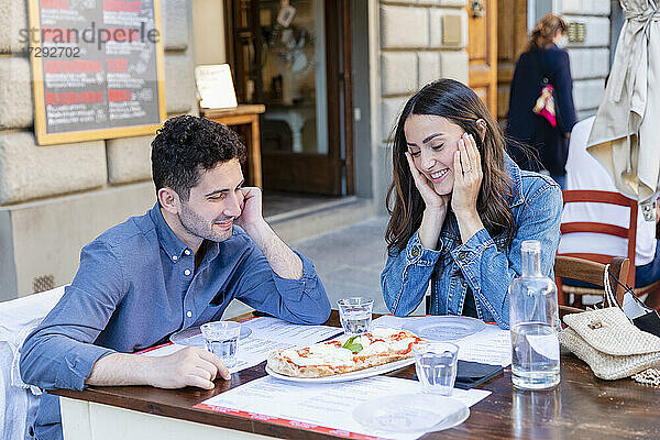 Paar lächelt bei der Betrachtung einer Pizza auf dem Tisch