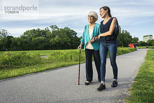 Lächelnde ältere Frau mit halbwüchsiger Frau auf dem Fußweg im Park