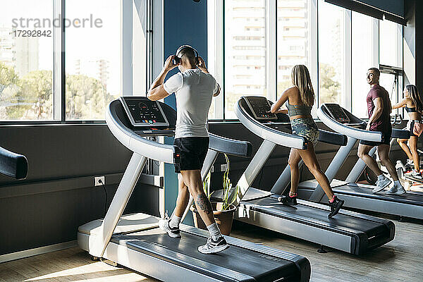 Männlicher und weiblicher Sportler beim Training auf dem Laufband im Fitnessstudio