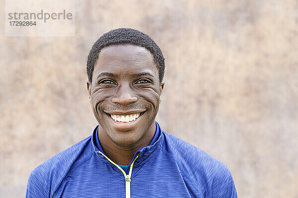 Lächelnder Afro-Mann vor einer Wand stehend