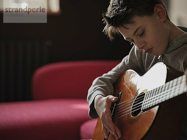 Junge lernt Gitarre zu Hause