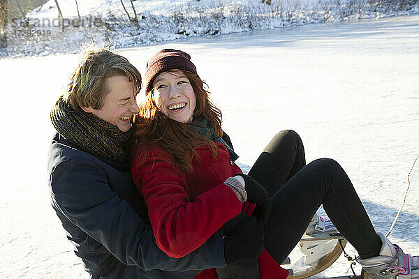 Verliebtes Paar hat Spaß beim Schlittenfahren auf dem Eis