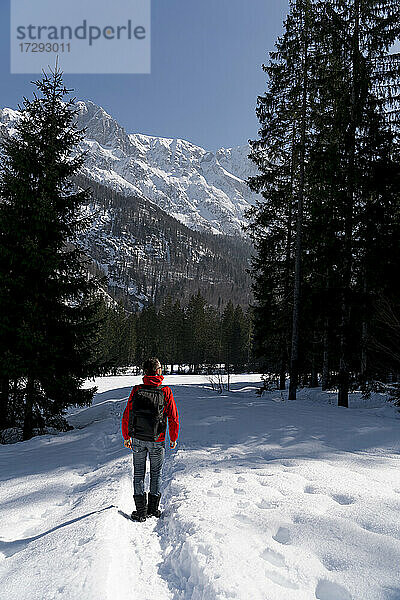 Mittlerer erwachsener Mann mit Rucksack beim Wandern im Schnee