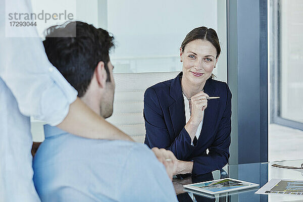 Lächelnde Geschäftsfrau im Gespräch mit einem männlichen und einem weiblichen Kunden