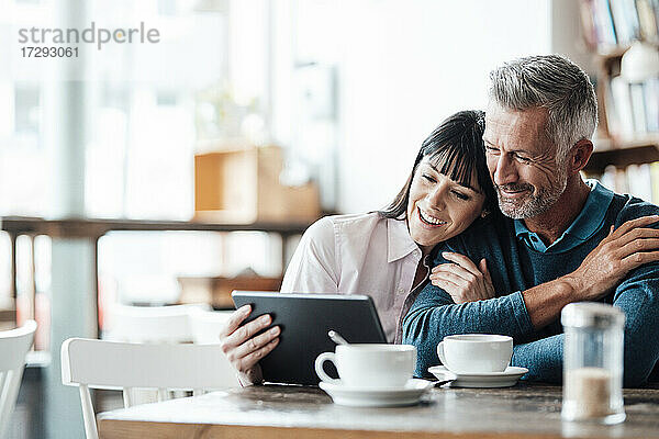 Geschäftspaar lächelt bei der Nutzung eines digitalen Tablets in einem Cafe