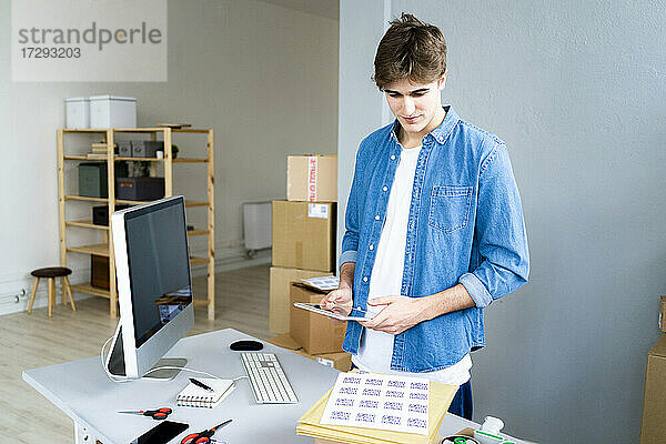 Männliche Fachkraft mit digitalem Tablet  die QR-Codes am Schreibtisch im Büro untersucht