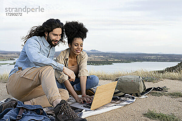 Mid adult couple using laptop while sitting on blanket