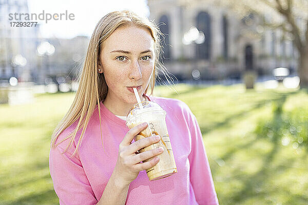 Schöne Frau trinkt Milchshake im öffentlichen Park