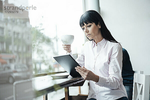 Geschäftsfrau  die ein digitales Tablet benutzt  während sie in einem Café sitzt