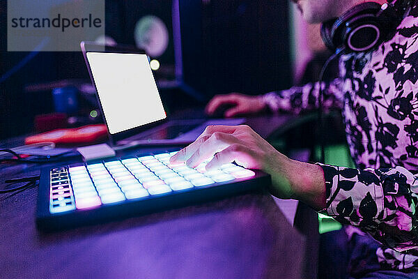 Männlicher Komponist beim Komponieren von Musik mit Laptop und digitalem Tablet im Studio