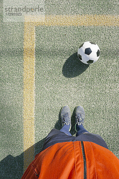 Mann steht vor einem Fußball auf einem Feld
