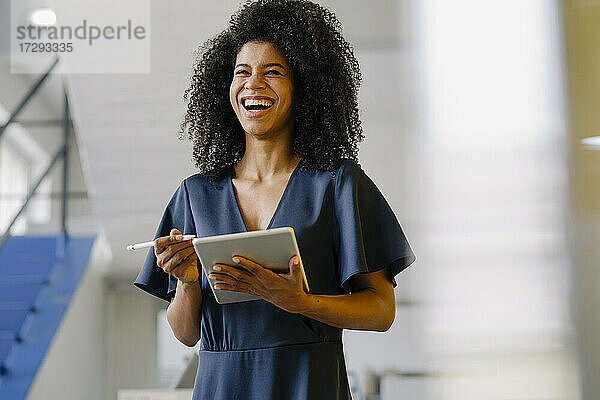 Weibliche Fachkraft mit digitalem Tablet lachend im Büro