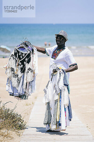 Männlicher Verkäufer verkauft Kleidung auf der Promenade am Strand