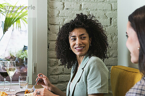 Lächelnde Geschäftsfrau  die einen Kollegen im Restaurant ansieht