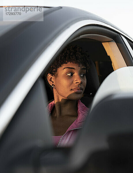 Nachdenkliche Frau  die im Auto vom Fenster wegschaut