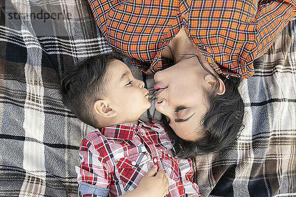 Sohn küsst Mutter  während er auf einer Picknickdecke liegt